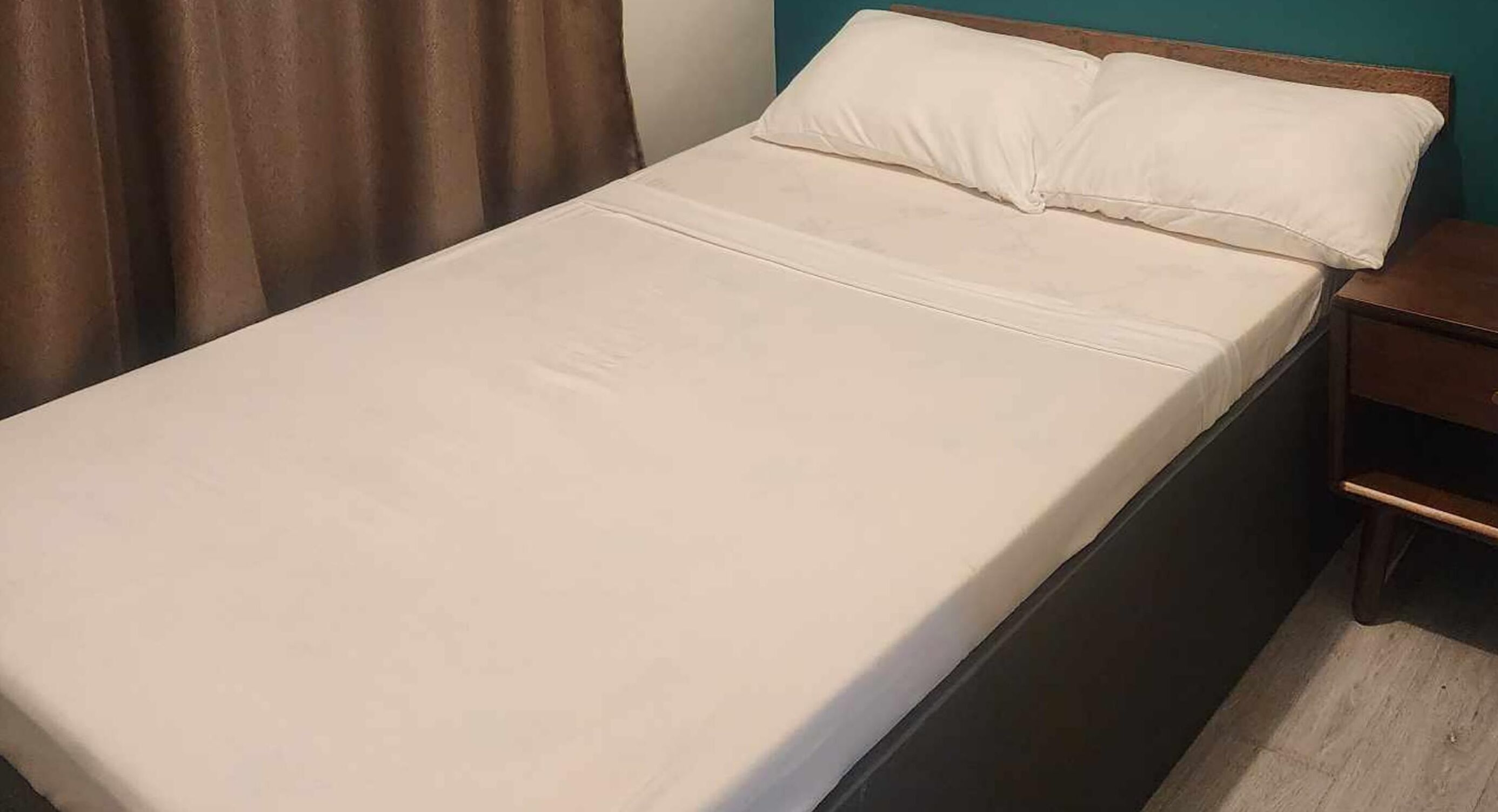A single bed with a wooden headboard and a white mattress.