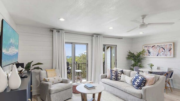 A living room with a sofa, armchair, coffee table, and a dining area with a table and chairs. - GULF VIEWS, Community Pool, Honeymoon Retreat, 50 Steps to Beach, Newly Decorated! 'BeeBy The Dunes' (Inlet Beach)