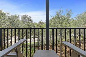 Relax on the balcony overlooking a serene garden with lush trees and shrubs.