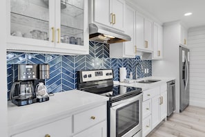 Enjoy cooking in this well-equipped kitchen with an oven, stainless steel range hood, and coffee maker.