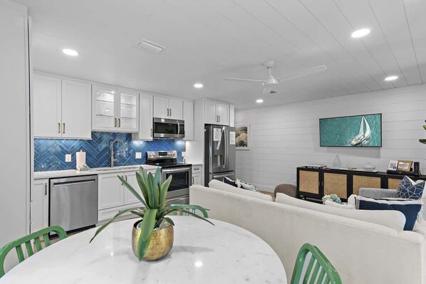Una cocina moderna con armarios blancos, electrodomésticos de acero inoxidable y salpicadero azul.