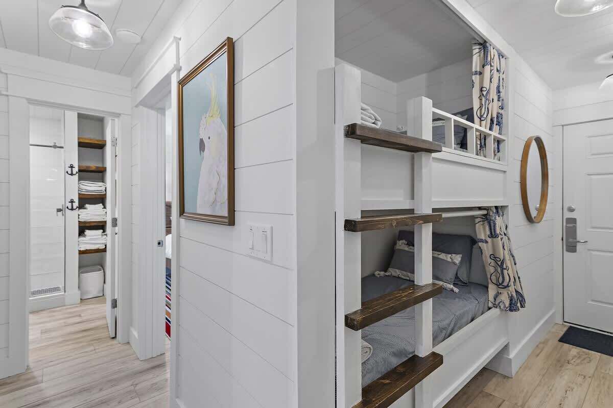 A bunk bed with a wooden frame, a white door, and a mirror on the wall.