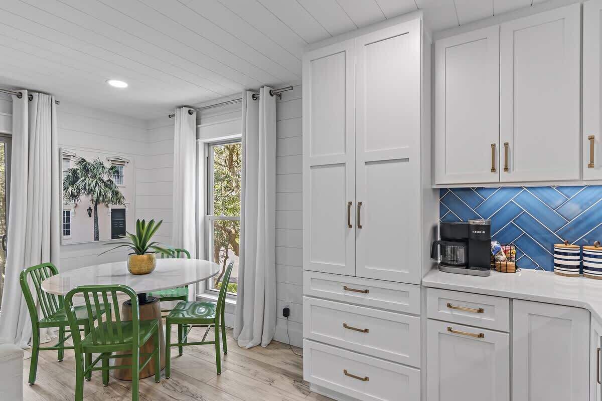 A kitchen with white cabinets, a coffee maker, and a blue tiled backsplash.