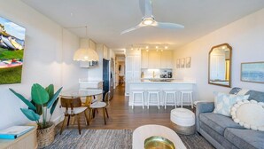 Una cucina moderna con mobili bianchi, un'isola centrale con sgabelli e una ventola a soffitto.