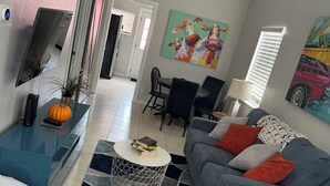 Ein modernes Wohnzimmer mit einem blauen Sofa, einem Couchtisch und einem an der Wand befestigten Fernseher.