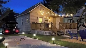 Ein Haus mit Terrasse, Lichterketten und einem Bereich für Rasenspiele.