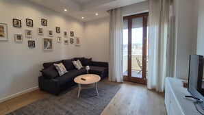 Ein modernes Wohnzimmer mit einem dunklen Sofa, einem runden Couchtisch und einem Fernseher auf einer weißen Kommode.