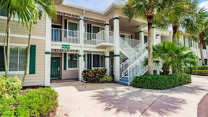 A multi-story hotel with a central staircase, balconies, and palm trees. - Stunning 3BR Naples Condo with Tropical Views (Naples)
