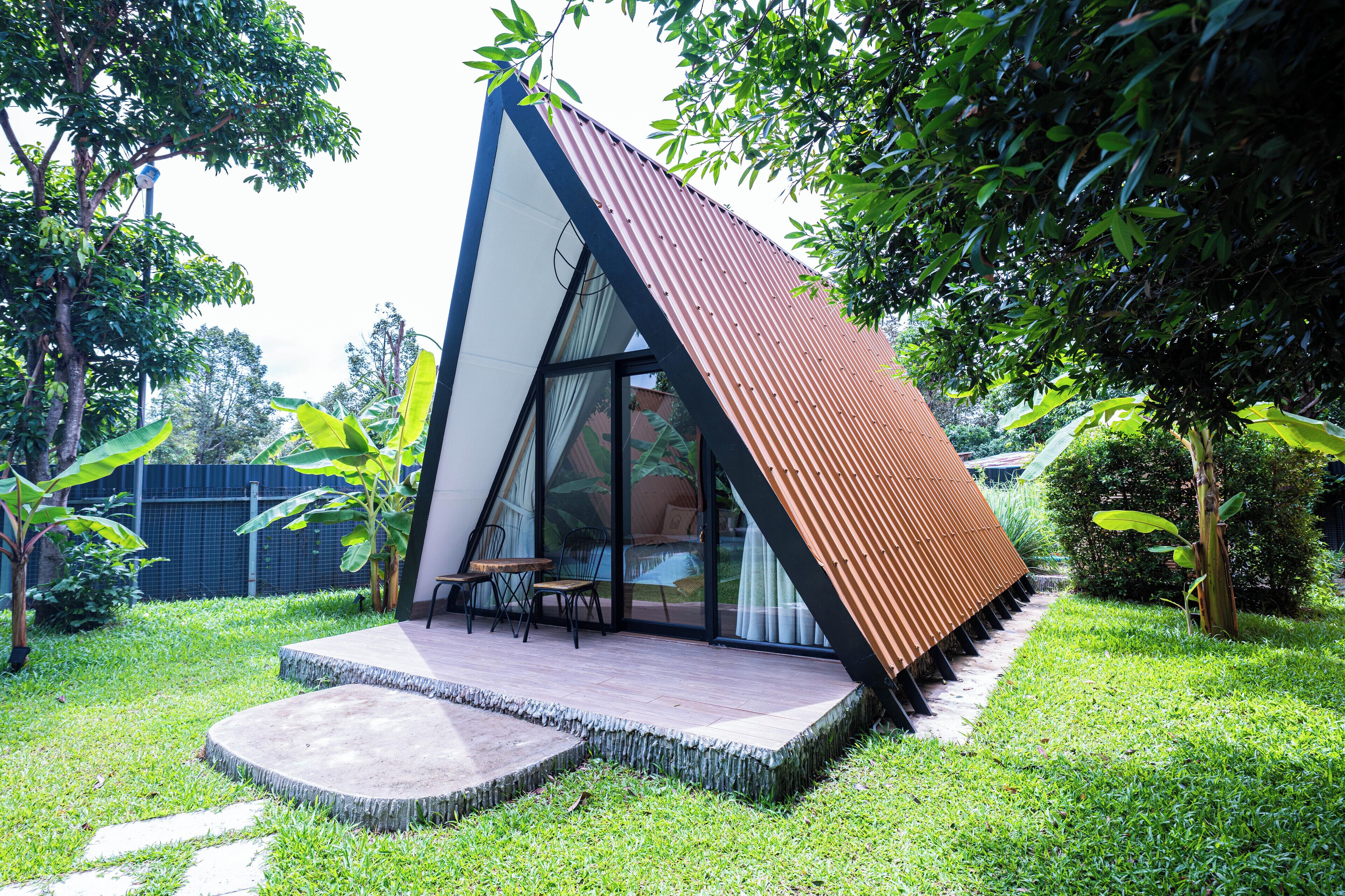 A modern house with a sloped roof, a glass door entrance, and a patio with outdoor furniture.