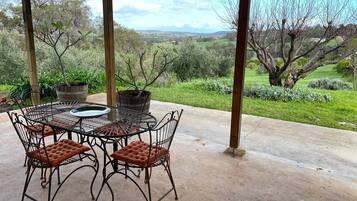 Relax on the patio surrounded by lush trees and rolling hills, with a round table and four comfortable chairs.