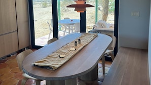 A modern kitchen with a wooden ceiling, a large window, and a dining area with a table and chairs. - Designer  2-bedroom house in wonderful Landers with AC, WiFi 365 views 2.5 acres (Landers)