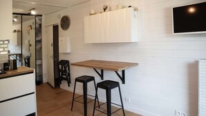 A kitchen with a wooden countertop, two black stools, a white cabinet, and a wall-mounted TV. - 2-person studio with superb view of the slopes (LES ORRES 1650)