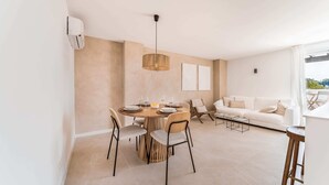 A modern living space with a dining area, a white sofa, and a view of the outdoors.