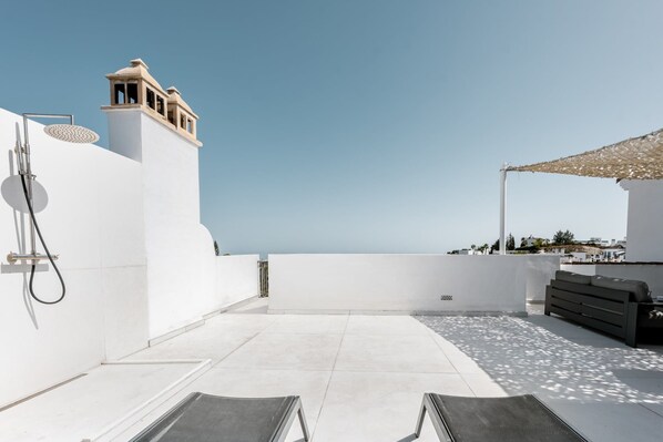 A rooftop terrace with a clear view of the sea, a pergola, and a modern outdoor seating area.