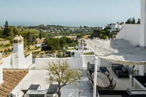 A rooftop terrace with outdoor seating, a view of a coastal town, and a clear sky. - Paraiso Pueblo 2 | Marbella Terrace Pools Gym (Benahavís)