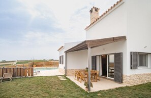 Una casa moderna con patio, piscina y vistas al campo.