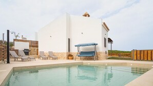 A modern pool area with a rectangular pool, lounge chairs, and a pergola with a blue canopy.