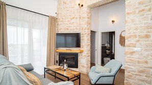 A living room with a stone wall, a fireplace, a television, and a sofa.