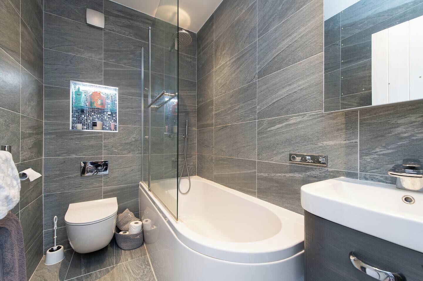 A modern bathroom with a freestanding bathtub, a separate toilet, and a glass-enclosed shower area.