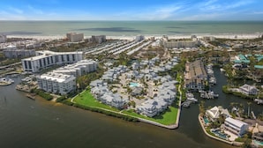 Zona residencial costera con un puerto deportivo, edificios modernos y una vista despejada del océano.