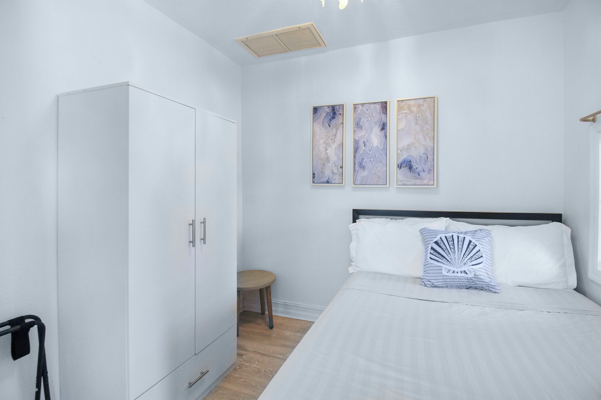 Una camera da letto con un letto, un armadio e tre dipinti astratti appesi al muro.
