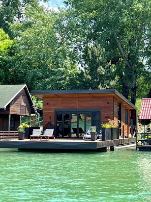 A modern wooden cabin with a deck, overlooking a body of water. - Beach House Belgrade (Belgrade)