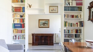 A living room with a sofa, a wooden dining table, and two bookshelves filled with books.