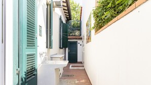 A narrow alleyway with a white sink, a green door, and a black door.