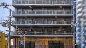 A multi-story building with balconies, a wooden facade, and visible utility poles. - Apartment Hotel 11 Tsutenkaku (Osaka)