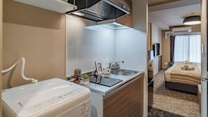 A compact hotel room with a kitchenette, a bed, and a bathroom. - Apartment Hotel 11 Tsutenkaku (Osaka)