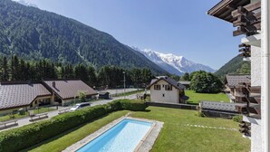 Zona residencial con piscina, casas de techos inclinados y montañas al fondo.