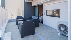 A modern outdoor patio with wicker furniture, a sliding glass door leading to a bedroom, and a standing fan. - Apartment Hotel 11 Umeda Kamiyama (Osaka)