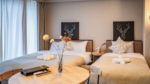 A hotel room with two beds, a round wooden table, and two chairs. There are two wall-mounted artworks depicting deer heads. - Apartment Hotel 11 Umeda Kamiyama (Osaka)
