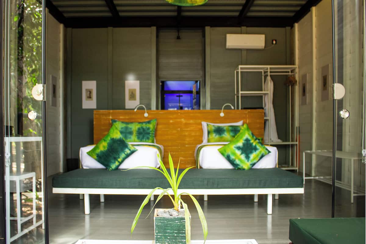 Une chambre d’hôtel moderne avec un grand lit, une literie aux couleurs verte et blanche, une petite plante et un téléviseur.