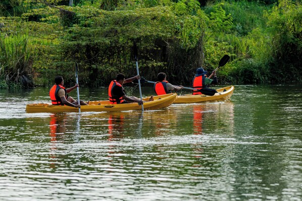 Three people kayaking in a calm river surrounded by lush greenery. - Waraka - Udawalawe (Udawalawa)