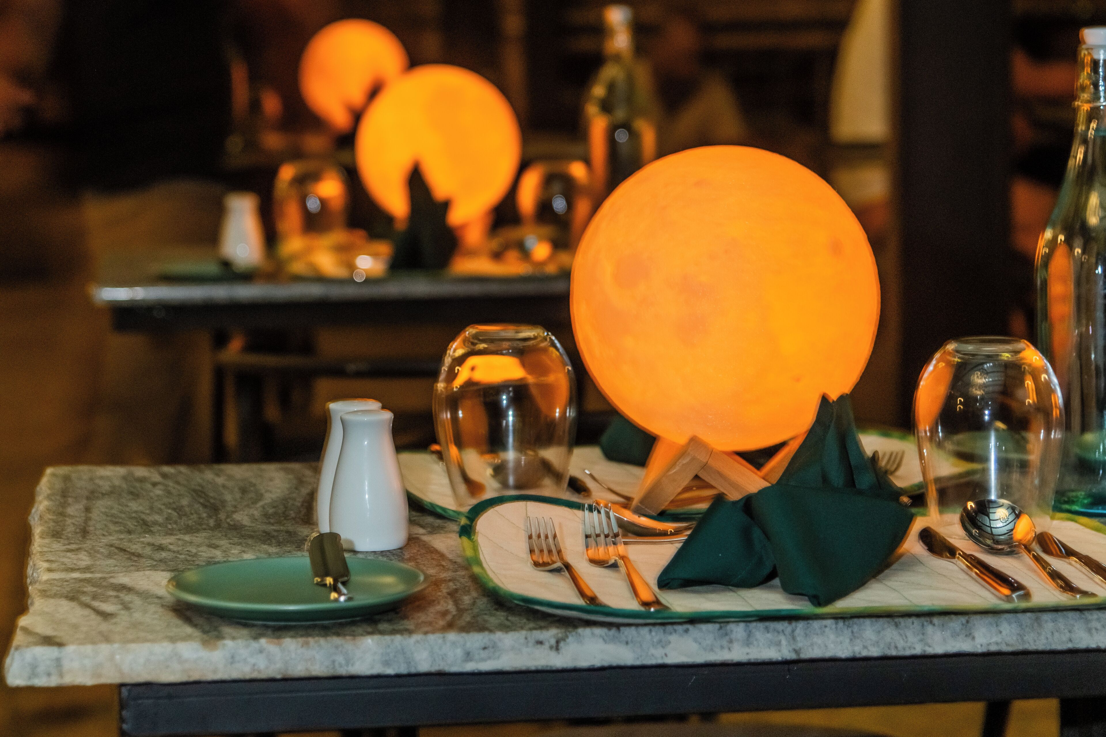 Una mesa dispuesta con platos, cubiertos y una servilleta verde.
