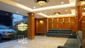 Un'accogliente hall d'albergo con un lampadario, un divano e una panca.
