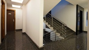 Un corridoio con una porta in legno con la targa 405, una scala con ringhiere in metallo e un moderno design del soffitto.