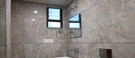 A modern bathroom with a white toilet, a small sink, and a shower.
