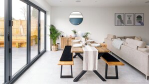 Un espace repas moderne avec une grande table, des bancs et un canapé.