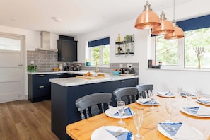 A modern kitchen with dark cabinetry, a marble island, and pendant lighting.