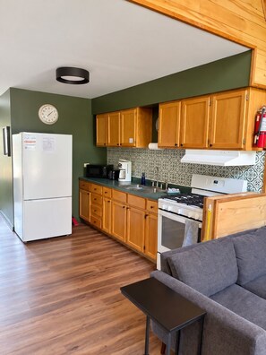 A compact kitchen with wooden cabinets, a white refrigerator, a stove, and a microwave.