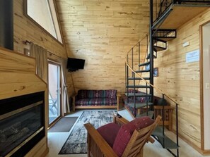 Un intérieur en bois avec un canapé, une cheminée et un escalier.