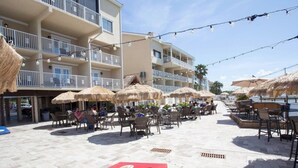 Eine Außenpatio-Terrasse mit Reetdachschirmen, Korbmöbeln und einem roten Tisch.