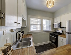 A kitchen with a double sink, stove, microwave, and cabinets. - Your Home Away from Home (Memphis)