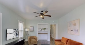 A living room with a ceiling fan, a TV, a sofa, a chair, and a bookshelf. - Your Home Away from Home (Memphis)