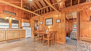 L’intérieur d’une cabane en bois comprend un coin repas, une cuisine et un espace de vie chaleureux.