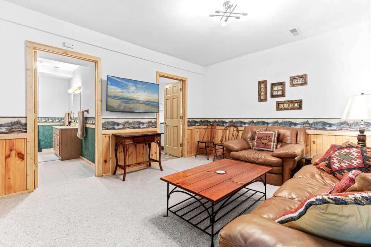 A living room with a wooden dining table, a leather sofa, and a painting on the wall.
