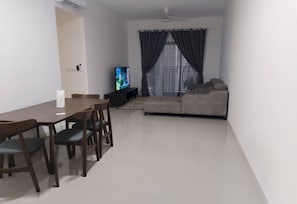 Una sala de estar con sofá, televisor, mesa de comedor y sillas.