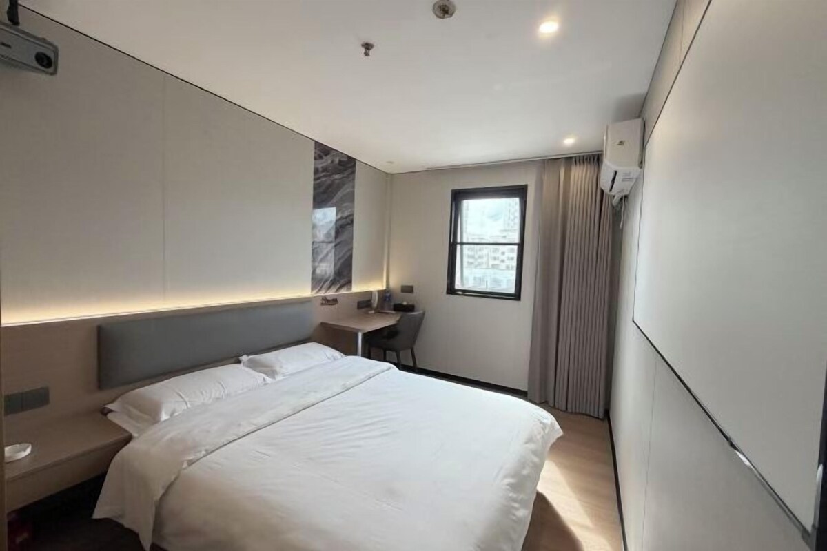 Quarto de hotel moderno com uma cama grande, uma escrivaninha e uma janela.